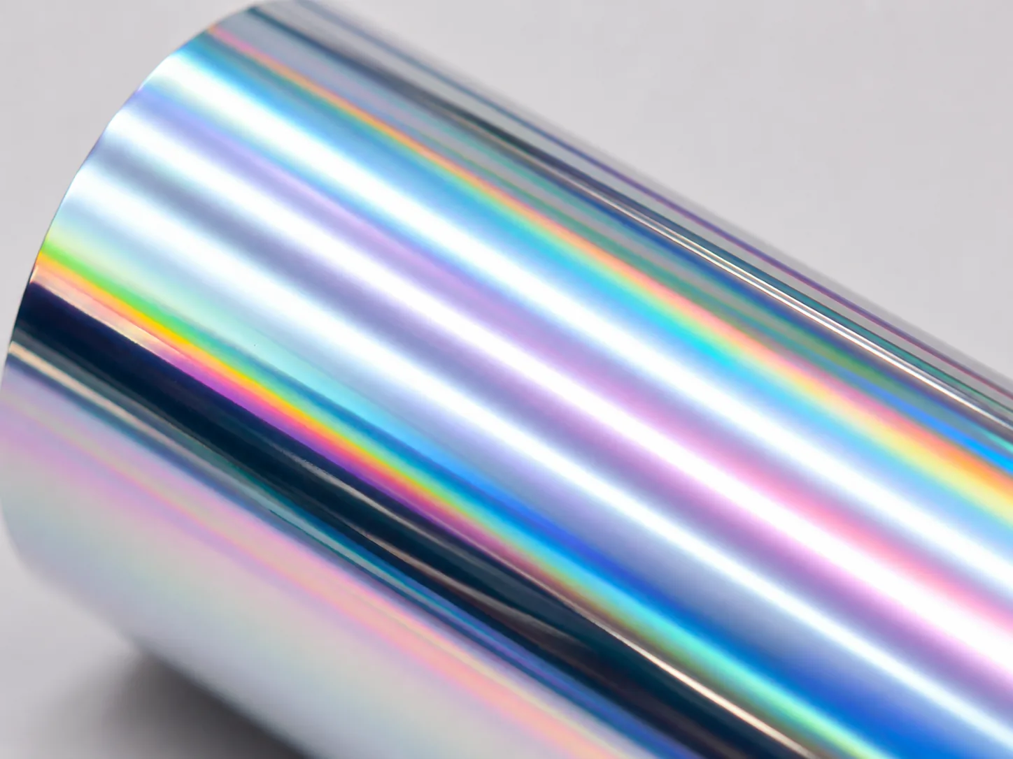 Macro detail of Holographic cold foil surface showing micro-embossed diffraction grating and full-spectrum rainbow play