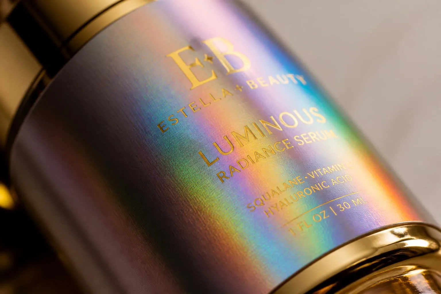 Macro detail of holographic rainbow cold foil label with gold foil text on a luxury cosmetics bottle