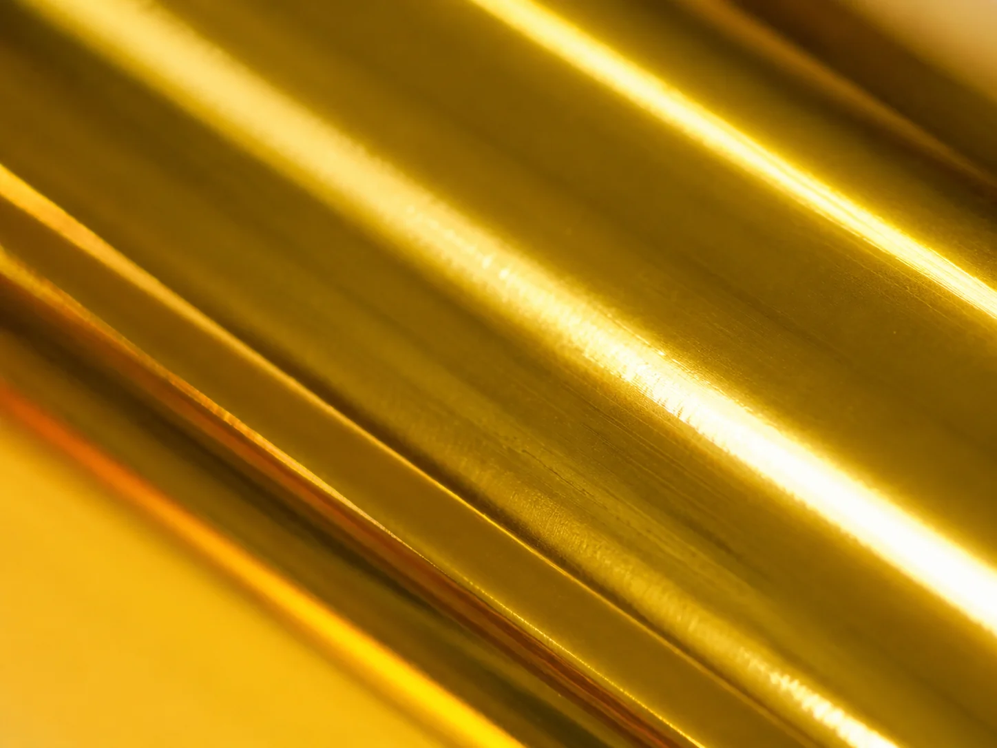 Macro detail of Bright Gold foil surface showing 92 GU mirror reflectivity and sub-micron particle alignment